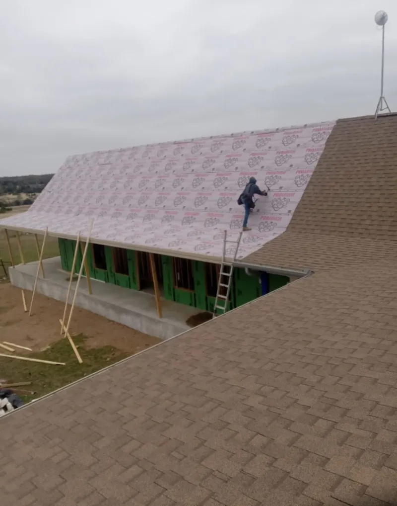 Worker preparing underlayment for a metal roof installation in Metropolis
